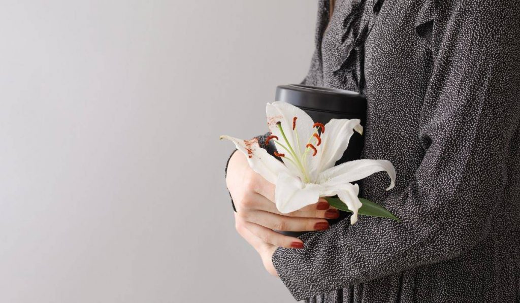 woman holding cremated ashes and lily